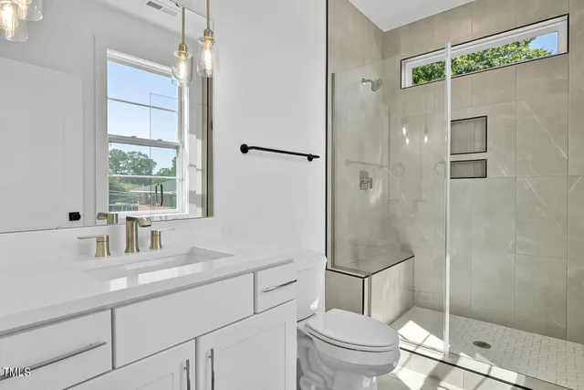 a bathroom with a granite countertop sink a toilet a mirror and shower