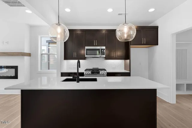 a large kitchen with stainless steel appliances a large center island attached withe living room