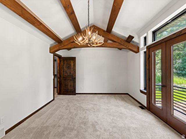 1225 Old Oregon Road Soda Springs, ID 83276 - Photo 40 of 67 Vaulted ceiling with exposed wood beams, antler-style chandelier, light carpeting, wood-finish French doors, and a rustic wood-panel door