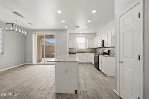 a kitchen with stainless steel appliances granite countertop a refrigerator a sink dishwasher a stove and white cabinets with wooden floor