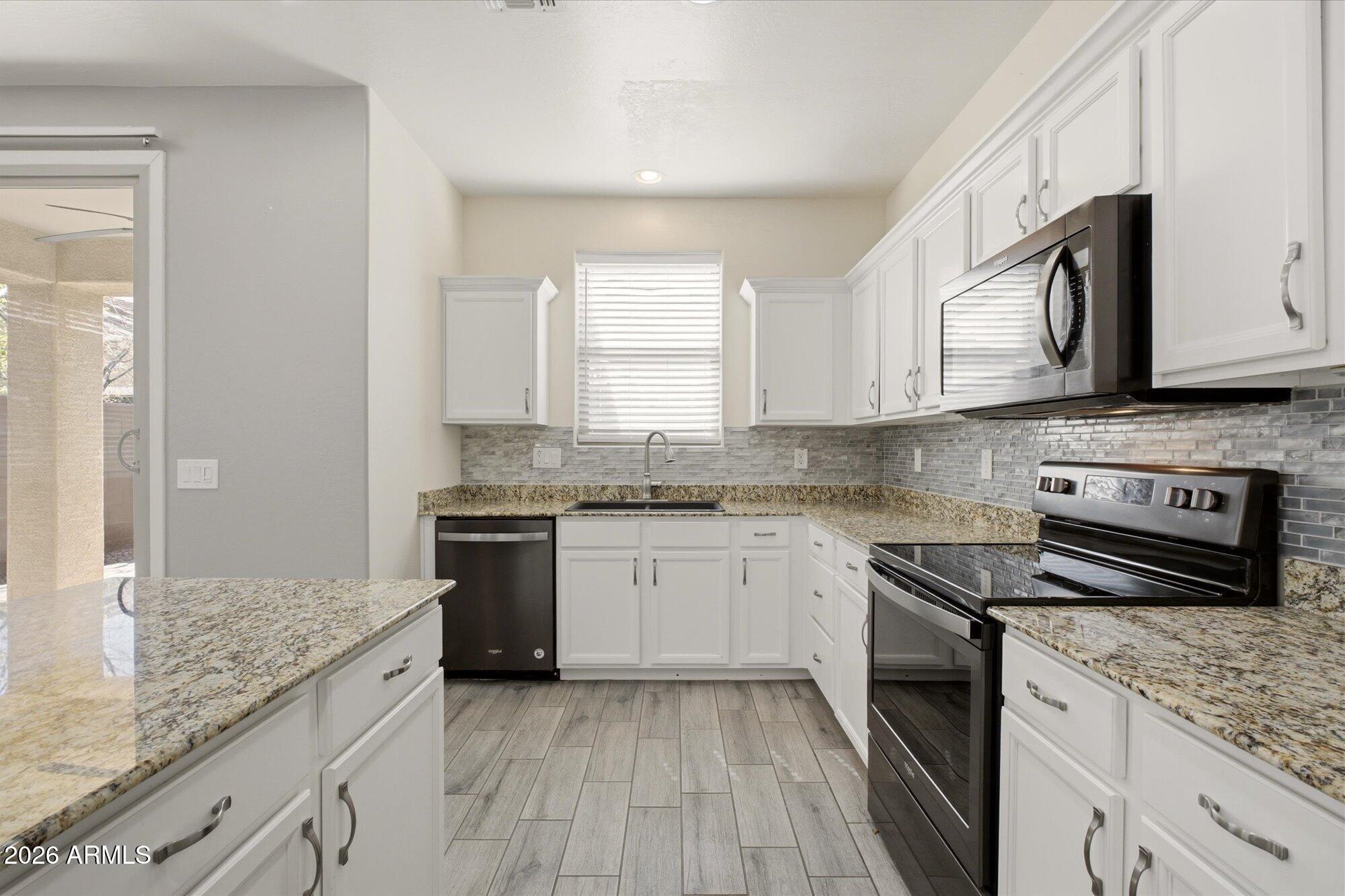 3347 East Roland Street Mesa, AZ 85213 - Photo 12 of 25 a kitchen with stainless steel appliances granite countertop a stove sink and cabinets