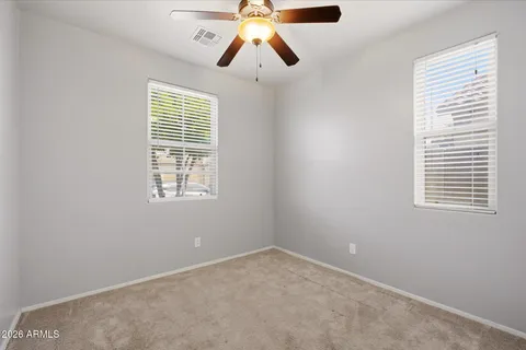 an empty room with chandelier fan and windows