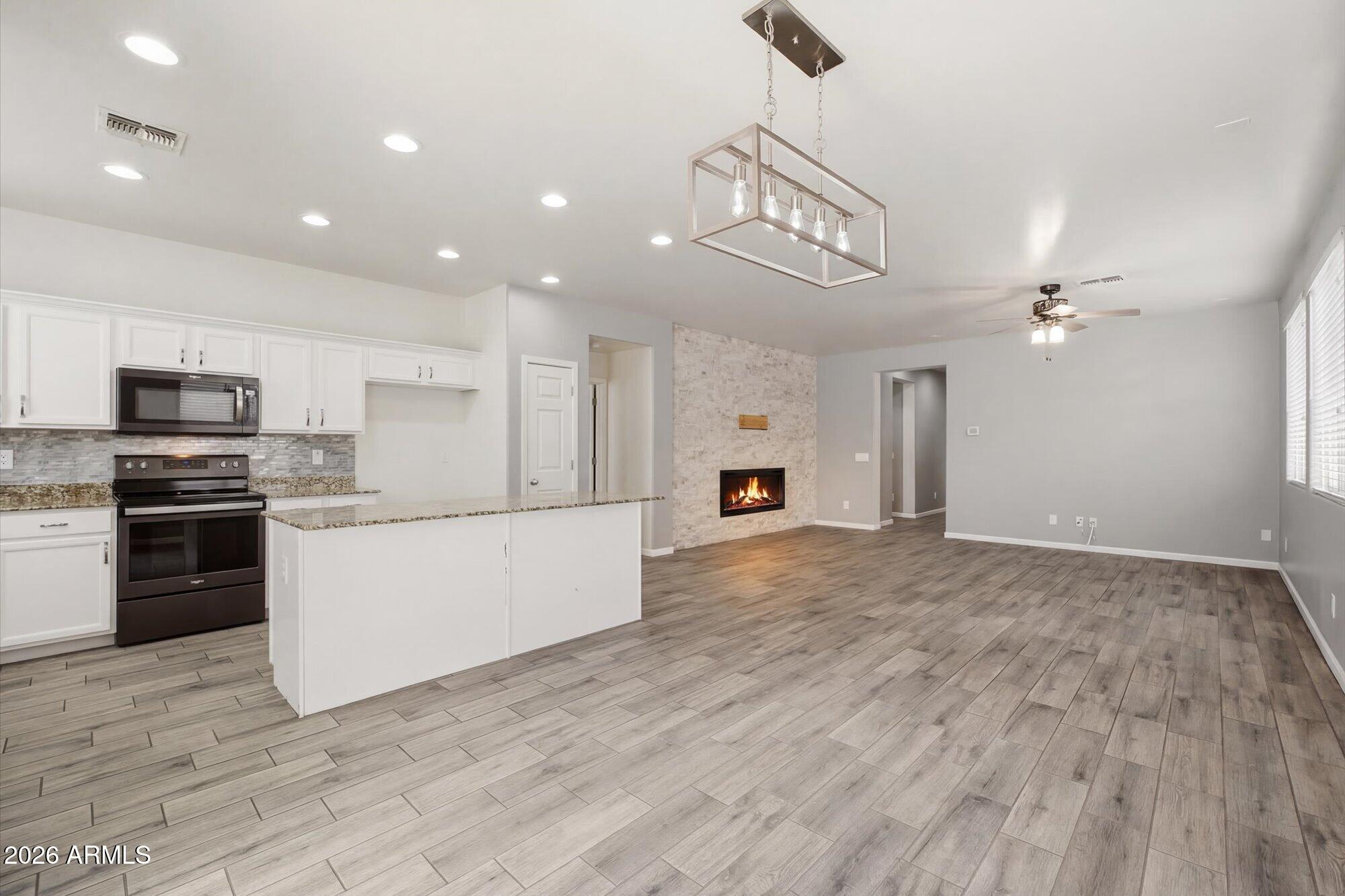 3347 East Roland Street Mesa, AZ 85213 - Photo 3 of 25 a large kitchen with stainless steel appliances granite countertop a large counter top and oven a sink with wooden floor