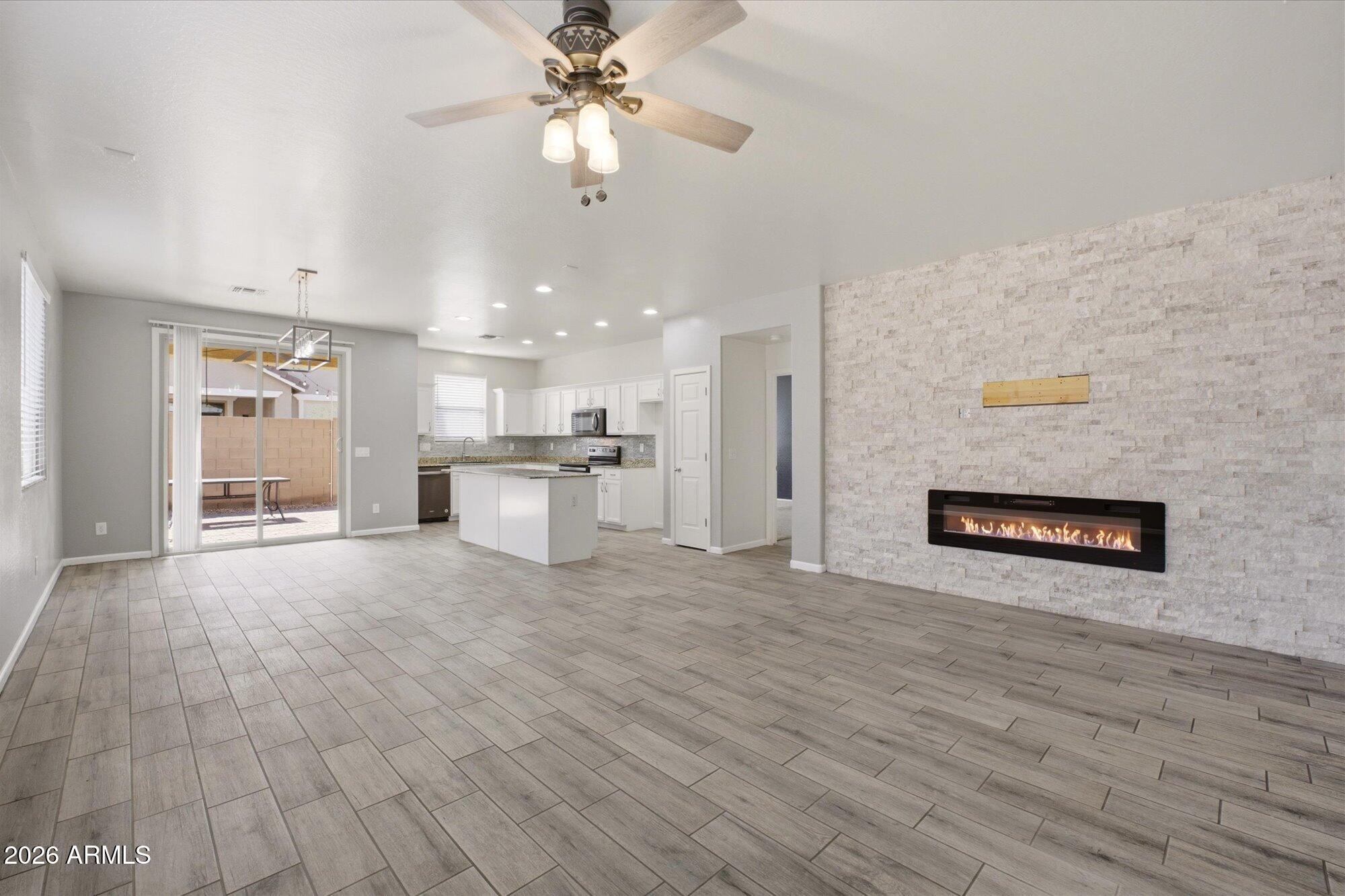 3347 East Roland Street Mesa, AZ 85213 - Photo 5 of 25 an empty room with wooden floor kitchen view and a ceiling fan