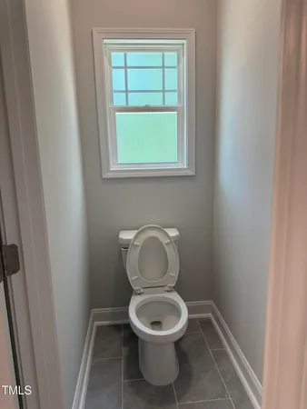 a white toilet sitting in a bathroom next to a window