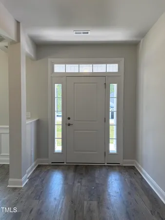 an empty room with wooden floor mirror and windows