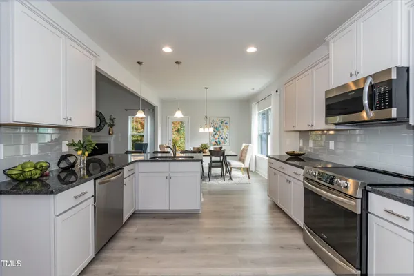 a kitchen with stainless steel appliances kitchen island granite countertop a sink a stove top oven a counter space and cabinets