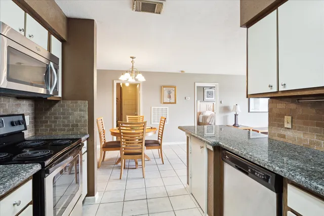 a kitchen with granite countertop a sink a stove and cabinets