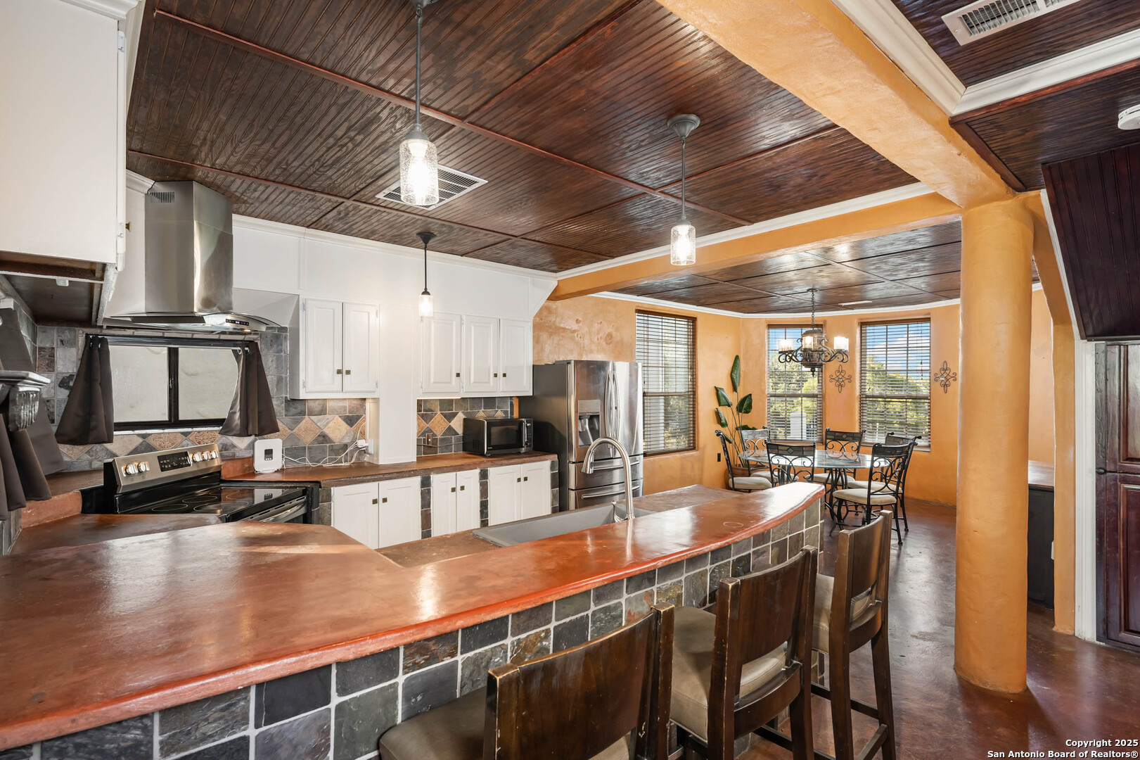 10655 Rebecca Creek Road Spring Branch, TX 78070 - Photo 10 of 34 a dining room with stainless steel appliances kitchen island granite countertop a table chairs and couches with wooden floor