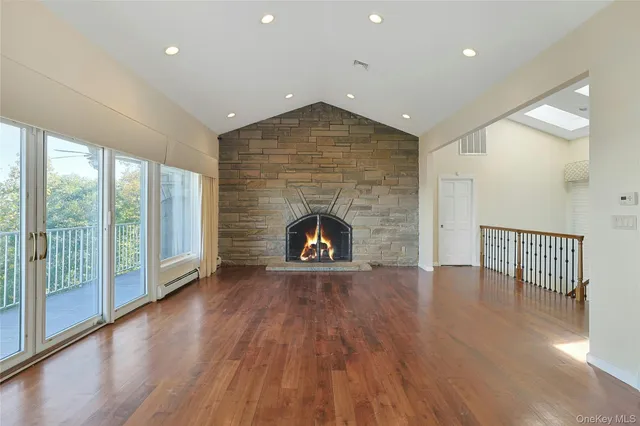 a view of an empty room with wooden floor fireplace and a window