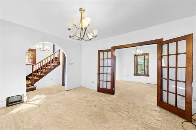 a view of an empty room with wooden floor windows and a chandelier
