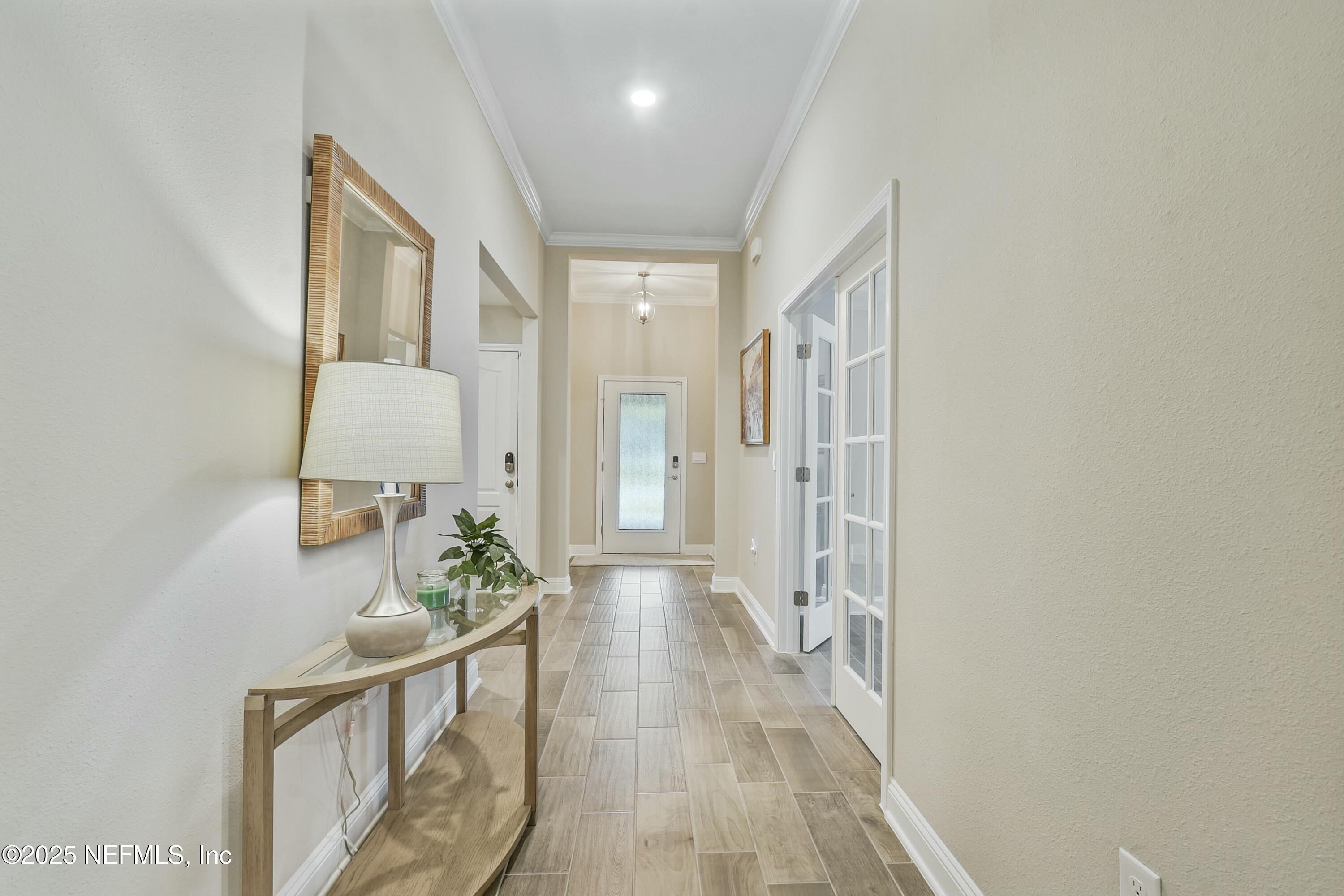 1399 Parkland Trail St. Augustine, FL 32095 - Photo 4 of 39 a view of a hallway to a livingroom with wooden floor and furniture
