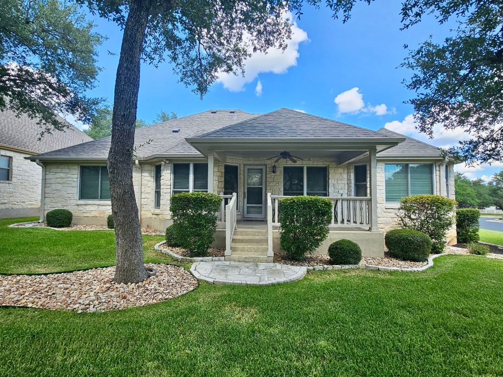 101 Texas Traditions Georgetown, TX 78628 - Photo 3 of 17 View of back of home featuring stone siding, covered porch, roof with shingles, and a front yard