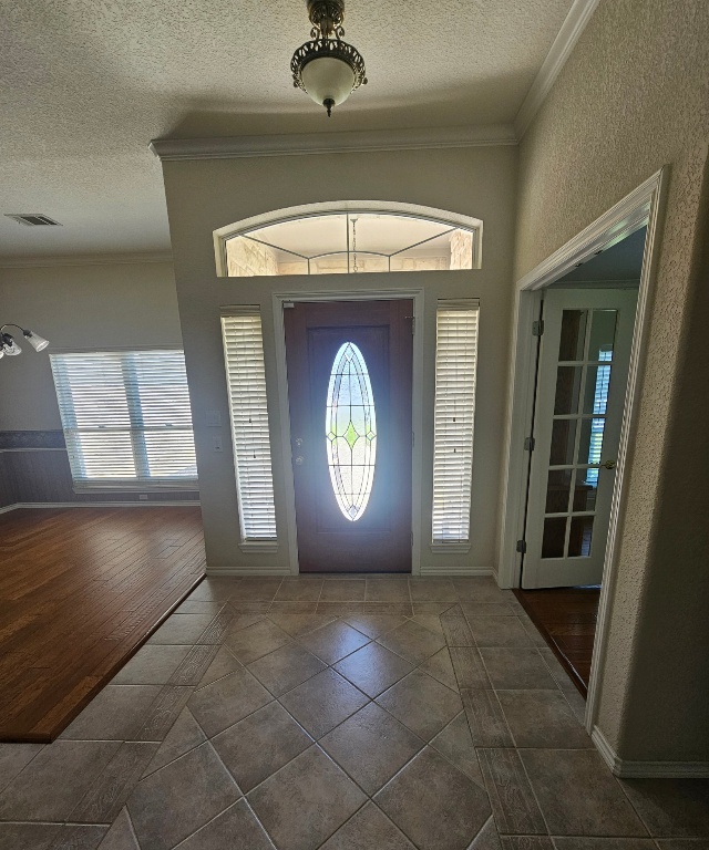 101 Texas Traditions Georgetown, TX 78628 - Photo 6 of 17 Entrance foyer featuring ornamental molding, tile patterned flooring, plenty of natural light, and a textured ceiling with crown molding through out