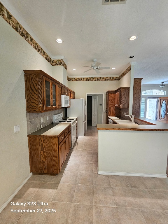 101 Texas Traditions Georgetown, TX 78628 - Photo 8 of 17 Kitchen featuring backsplash, a ceiling fan, white appliances, cabinets, and a peninsula