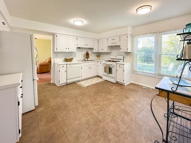 a kitchen with a stove a refrigerator and white cabinets with wooden floor