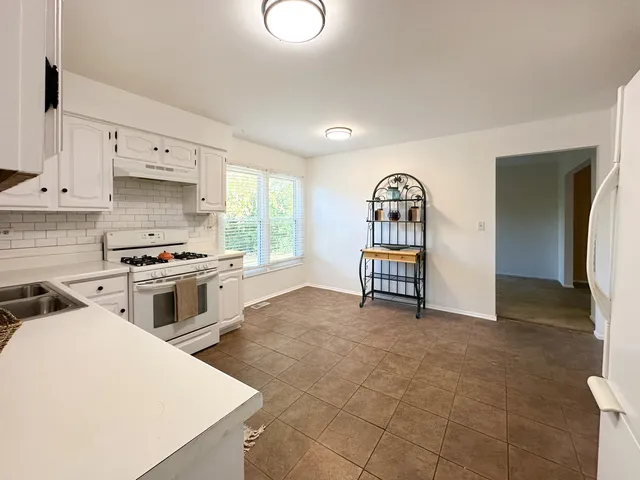 a kitchen with granite countertop a stove a sink and a refrigerator