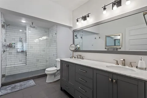 a bathroom with a double vanity sink toilet mirror and shower