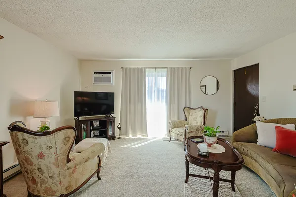 a living room with furniture a flat screen tv and a window