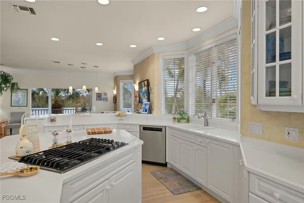a kitchen with stainless steel appliances a stove a sink and white cabinets