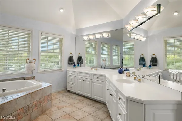 a bathroom with a granite countertop sink mirror bathtub and next to a window