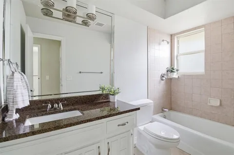 a bathroom with a granite countertop tub sink and mirror
