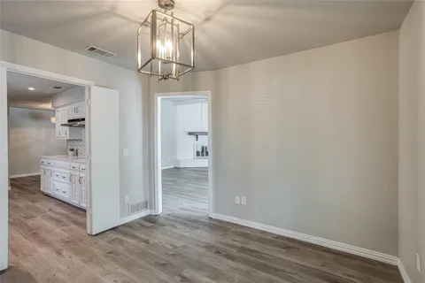 a view of a hallway with wooden floor and a chandelier