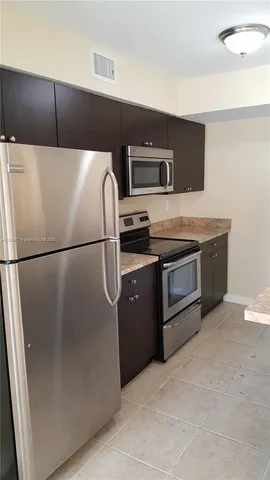 a kitchen with stainless steel appliances granite countertop a refrigerator and a stove