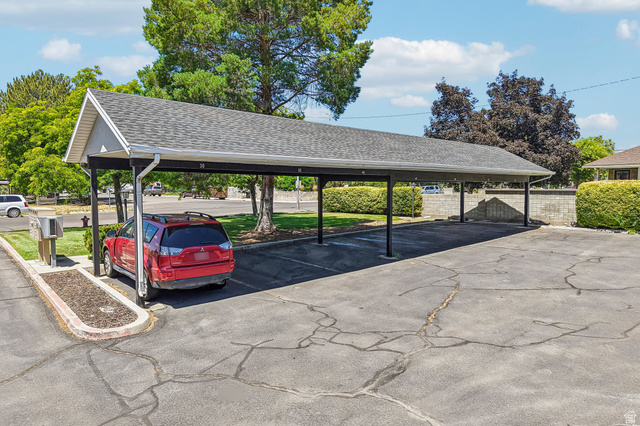 888 600 West, Unit 40 Provo, UT 84604 - Photo 16 of 19 Carport structure featuring a gabled roof with asphalt shingles, metal support posts, and integrated rain gutters