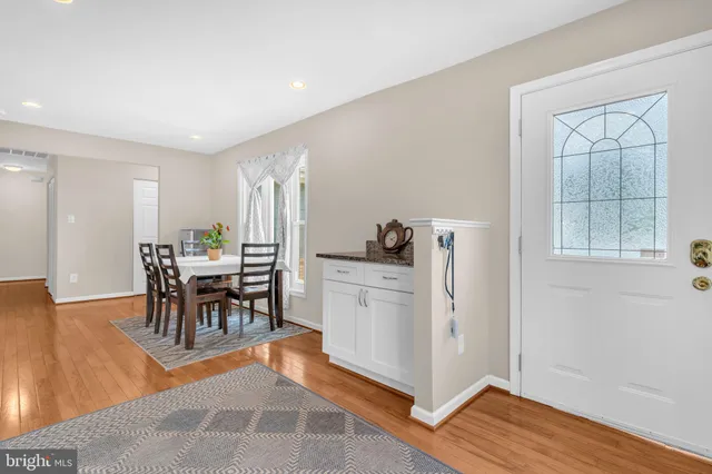 a dining room with stainless steel appliances granite countertop furniture and a wooden floor