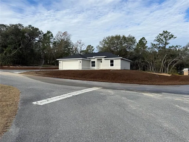 a front view of a house with a yard and trees in the background