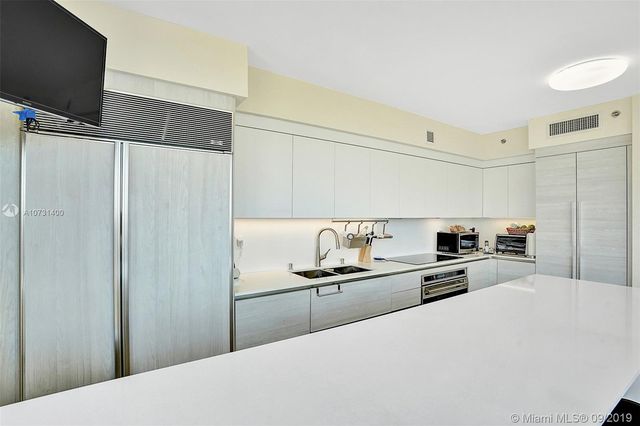 a kitchen with granite countertop a refrigerator a sink a stove and oven