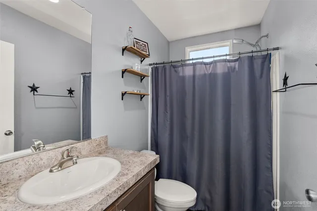 a bathroom with a granite countertop sink toilet and a mirror