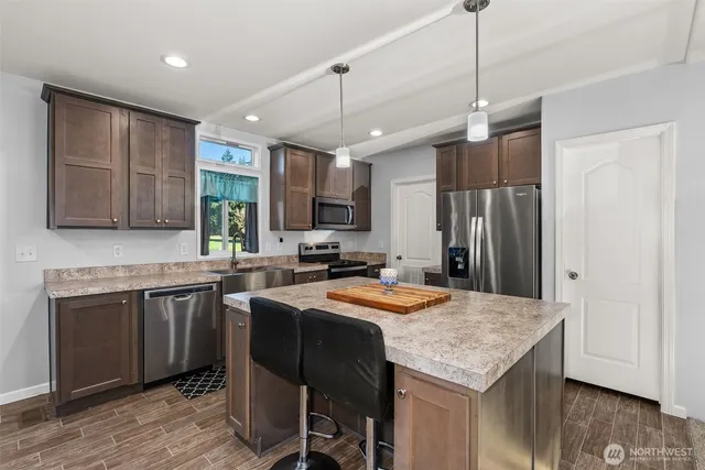 a kitchen with stainless steel appliances granite countertop a sink a stove a refrigerator cabinets and chairs
