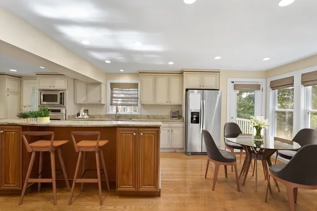 a kitchen with refrigerator a sink dining table and chairs
