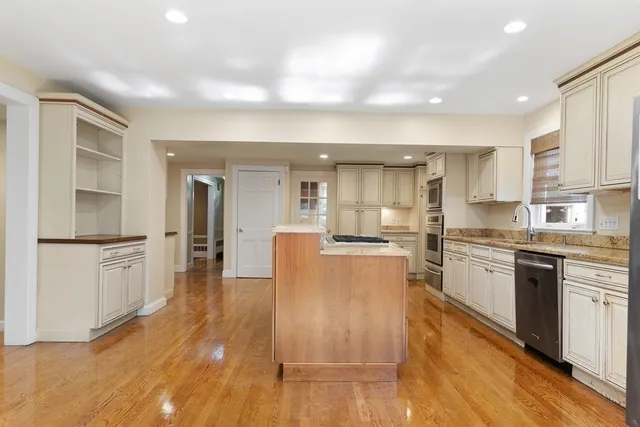 a kitchen with stainless steel appliances granite countertop a refrigerator a stove and white cabinets with wooden floor