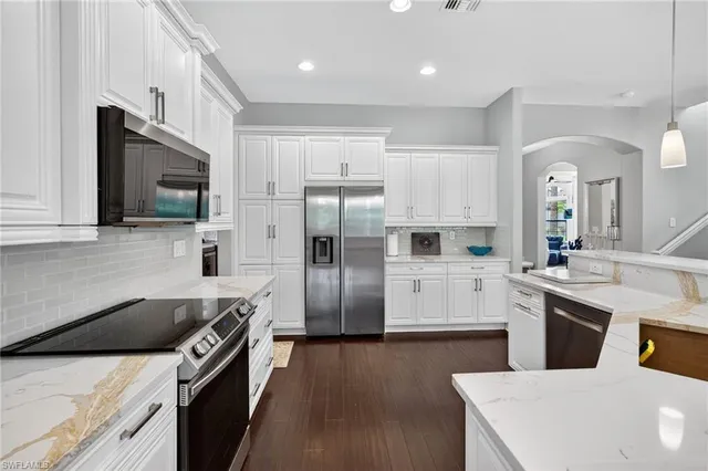 a kitchen with stainless steel appliances white cabinets a sink a stove a refrigerator and microwave