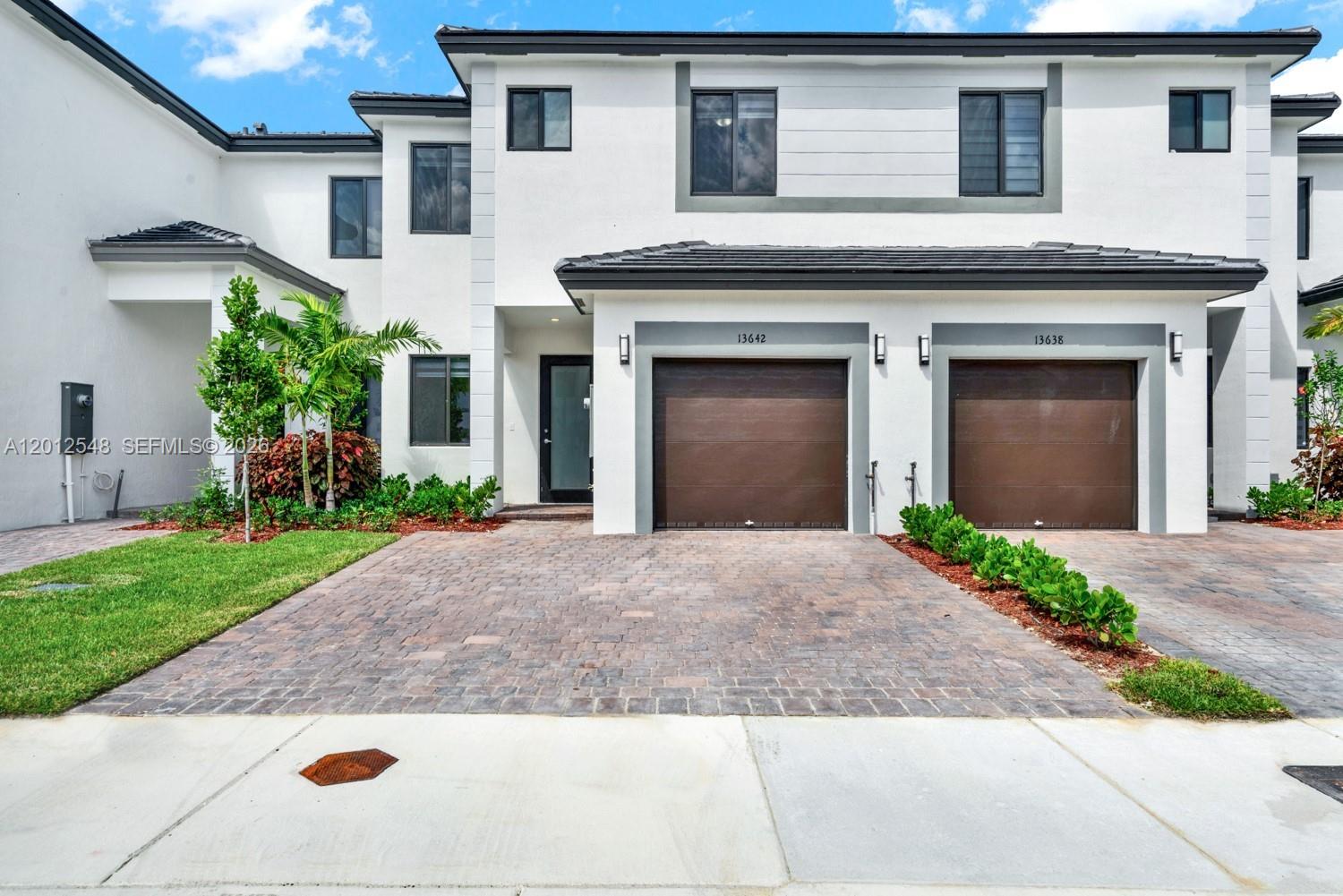 13642 Southwest 157th Place, Unit 13642 Miami, FL 33196 - Photo 40 of 41 a front view of a house with a yard and a garage