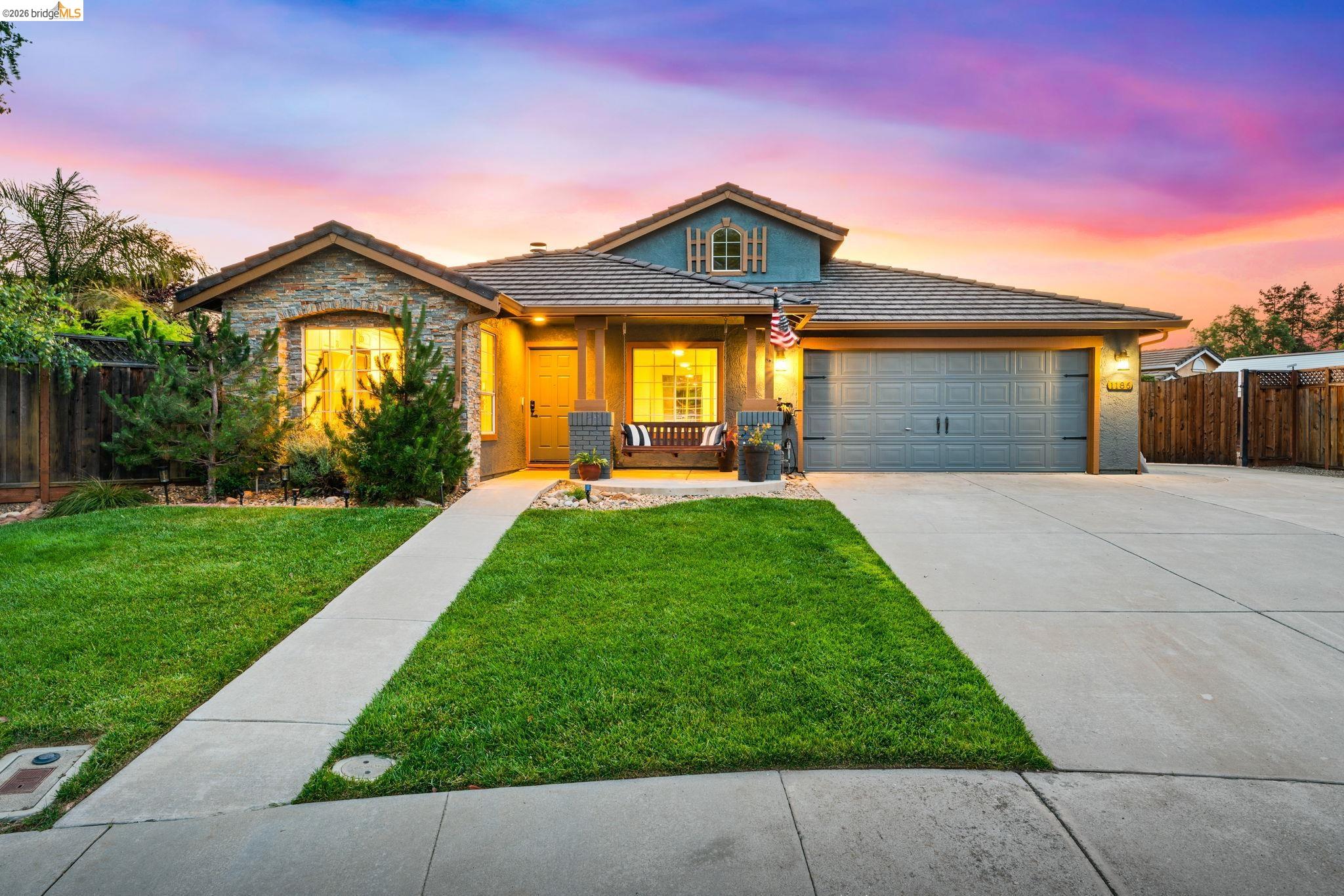 1186 El Rio Court Livermore, CA 94551 - Photo 56 of 60 Stone facade home with a tile roof, an integrated two-car garage, a concrete driveway, and a manicured lawn