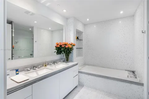 a bathroom with a granite countertop sink a large mirror and a bathtub