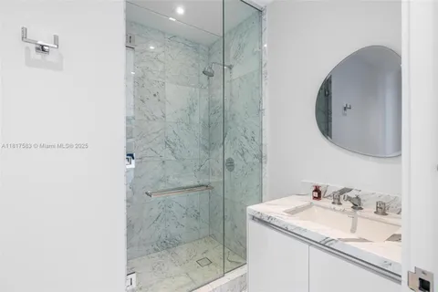 a bathroom with a granite countertop sink a mirror and shower