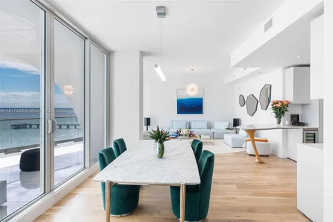 a living room with chairs kitchen view and a wooden floor
