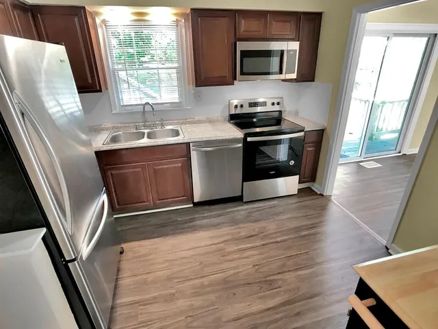 a kitchen with stainless steel appliances a stove a sink a microwave a refrigerator and a window