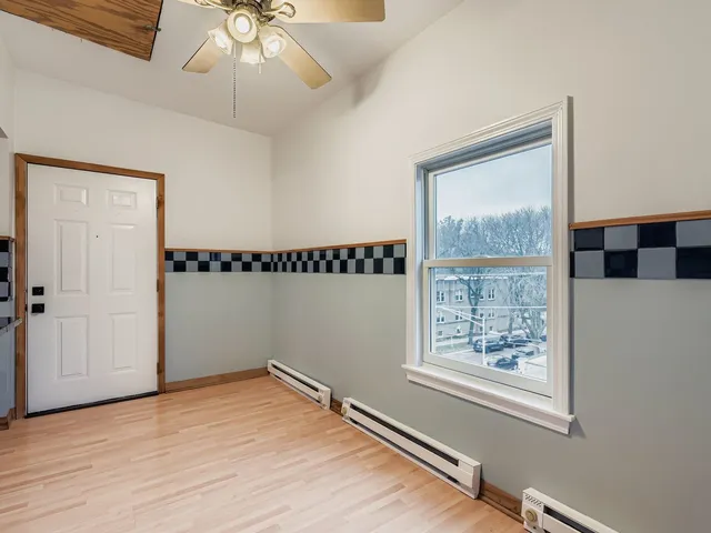 a view of an empty room with a window and wooden floor