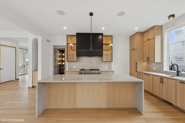 a large kitchen with stainless steel appliances granite countertop a sink a stove and a wooden floor