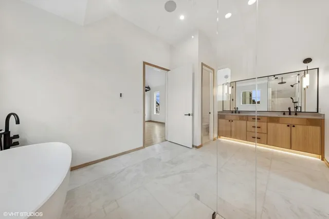 a large white bathroom with a tub sink and mirror