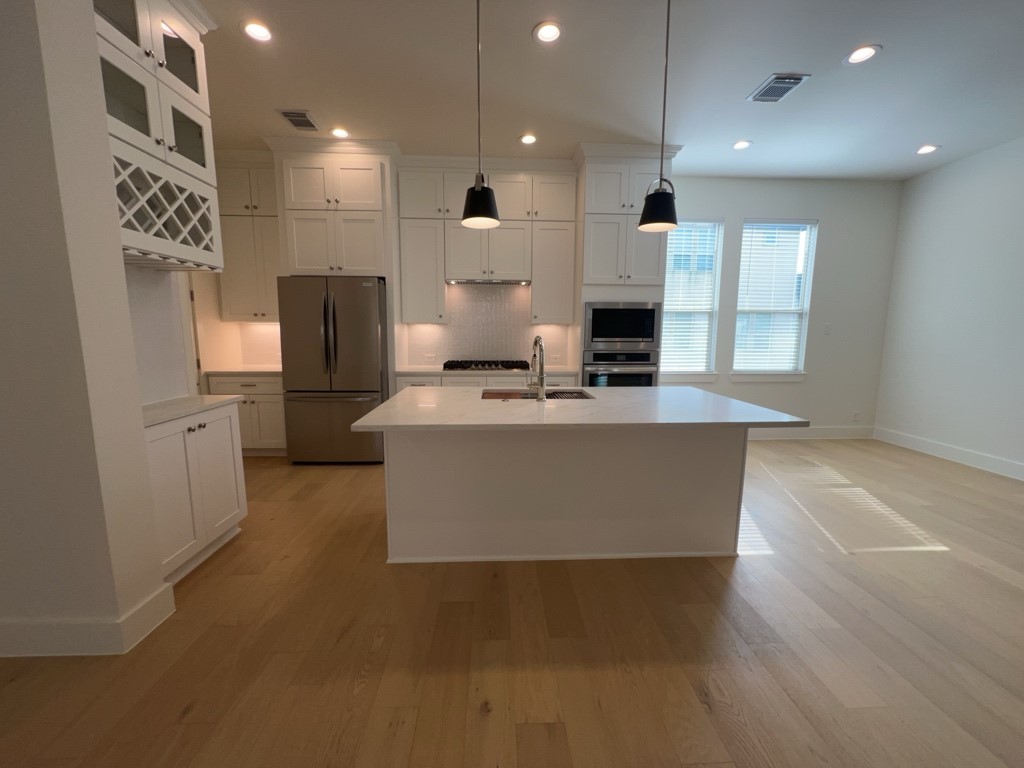 10607 Enclave Shadows Court Houston, TX 77043 - Photo 2 of 23 a large kitchen with stainless steel appliances kitchen island granite countertop a stove top oven a sink and a refrigerator
