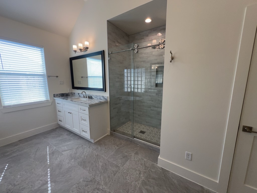 10607 Enclave Shadows Court Houston, TX 77043 - Photo 6 of 23 a bathroom with a granite countertop sink a mirror and shower