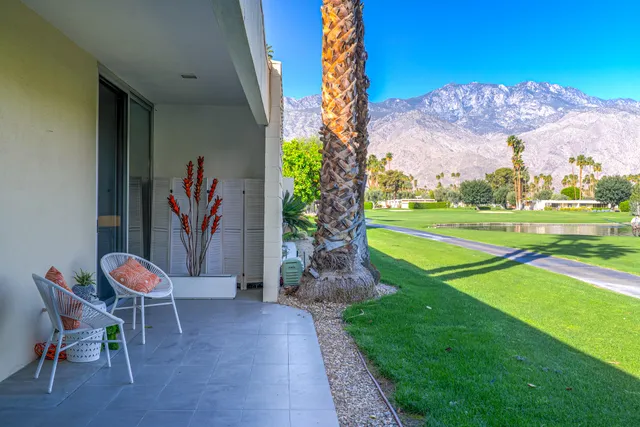 a view of swimming pool with lawn chairs and large trees
