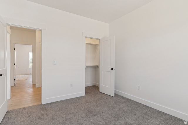 5777 West 4100 South Hooper, UT 84315 - Photo 18 of 41 Unfurnished bedroom featuring light carpet and a walk in closet